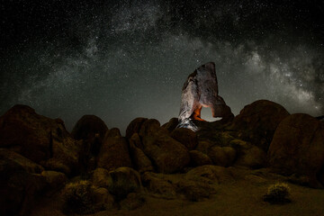 Aced Galaxy milky way surrounded by stars with a hollowed rock on foreground	
