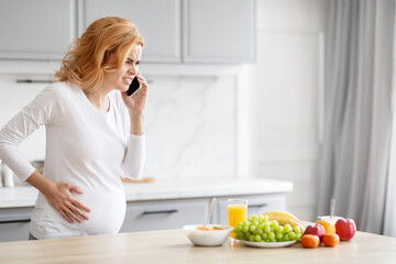 Obraz na płótnie Canvas Pregnant woman talking on phone in kitchen, feel sick