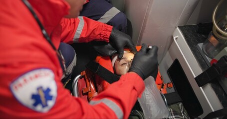 Patient, paramedic and shine light into eyes to check pupil, test and first aid. Hands, medical professional and flashlight to woman, unconscious and rescue for health, emergency or help in ambulance