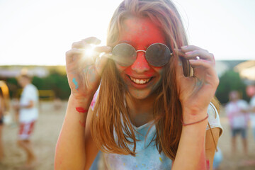 Happy woman covered in rainbow colored powder celebrating holi color festival. Young woman having...