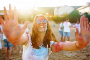 Happy woman covered in rainbow colored powder celebrating holi color festival. Young woman having...