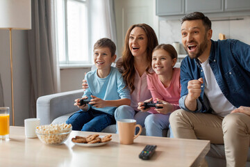 Family joyfully playing video games together, home interior