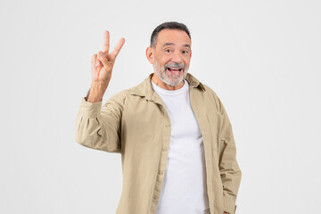 Cheerful senior man showing peace sign with a smile