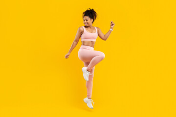 Lively black woman hopping with joy on yellow