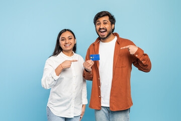 Fototapeta premium Happy couple showing a credit card on blue background