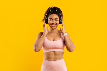 Smiling african american woman with headphones on yellow