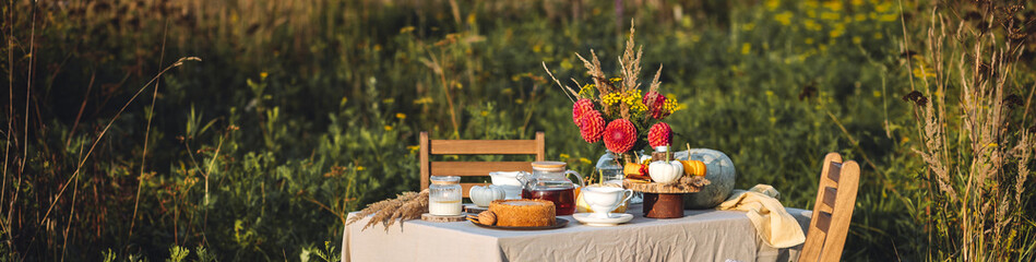 Tea setting with handmade pie. Beautiful view of garden wooden furniture with basket, soft blanket...