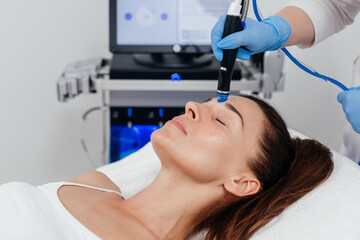 Middle aged woman receiving hydro facial lifting procedure. Natural, mature woman face with healthy freckle skin texture. Aesthetic, facial and skincare cosmetology