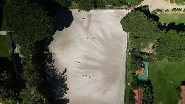 Top down aerial view over a show jumping course as a rider and horse jump the obstacles. Captured in Cascais, Portugal