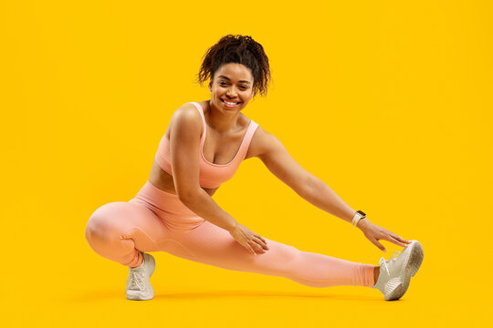 Fototapeta Energetic black woman doing a fitness side lunge