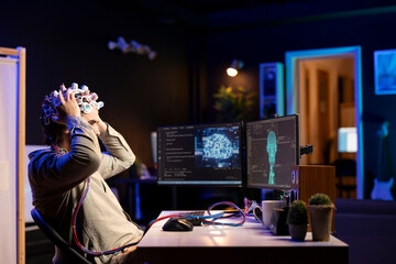 Software developer specializing in artificial intelligence putting EEG headset on to upload...