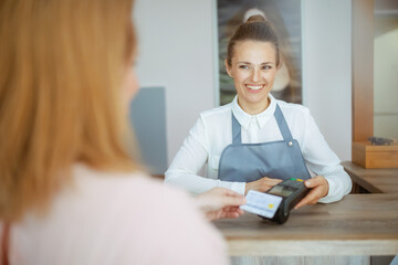 woman hairdresser accepting credit card payments via terminal - 784788769