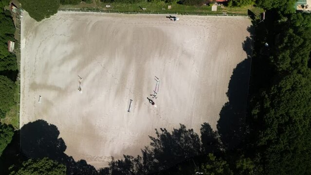 Top down aerial view over a show jumping course as a rider and horse jump the obstacles. Captured in Cascais, Portugal