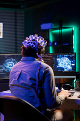 Software technician with EEG headset on programming brain transfer into computer virtual world,...