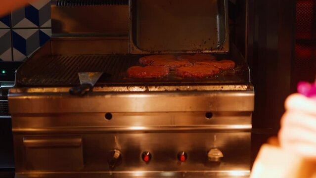 Sizzling Sensations: Nighttime footage of meat being expertly grilled in the kitchen of a burger restobar, creating mouthwatering aromas and flavors.