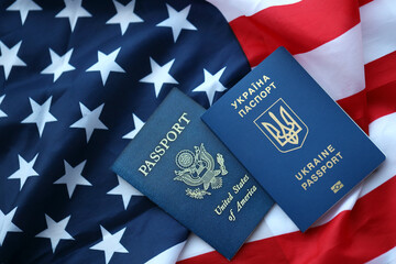 Passport of Ukraine with US Passport on United States of America folded flag close up