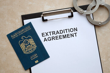 Passport of United Arab Emirates and Extradition Agreement with handcuffs on table close up