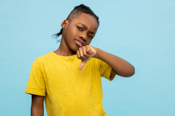 Disappointed African American little boy showing dislike gesture