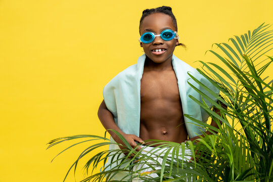 Cute african american boy in swimming eyeglasses and with towel on his shoulder