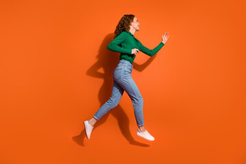 Full length photo of excited positive lady dressed green shirt jumping running emtpy space isolated orange color background
