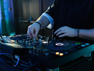 DJ plays live set and mixing music on turntable console at stage in the night club. Disc Jokey...