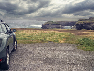 Car roof with sky reflection stunning Kilkee cliff in the background. Dramatic sky. Travel and...