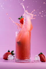 strawberries fall into cold lemonade on a pink background. A beautiful splash of liquid is frozen