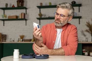 Diabetic man with glucometer checking blood sugar level at home