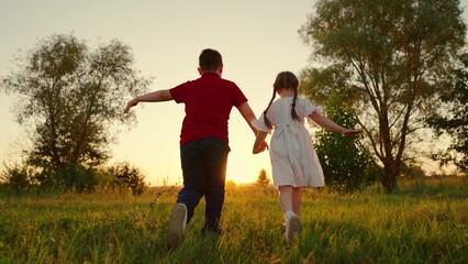 Young children dream fly. Child Boy girl holding hands run across field. Kids play in park. Brother...