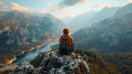 Tuinposter A man sits on a mountain top with a backpack on © ART IS AN EXPLOSION.