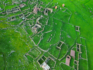  remains of an ancient mountain city in green grass - drone photo