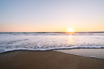Fototapeta na wymiar Evening tranquility as sun sets and waves caress shore.
