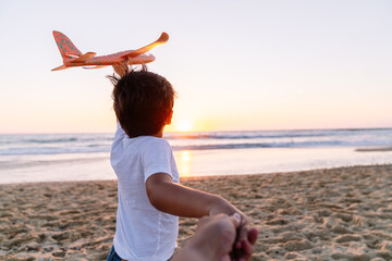 Child in motion, casting a toy plane into the sky.