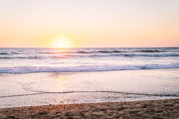 Soft sunset over a peaceful ocean and sandy beach.