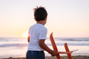Boy with toy plane, contemplating the sunset.