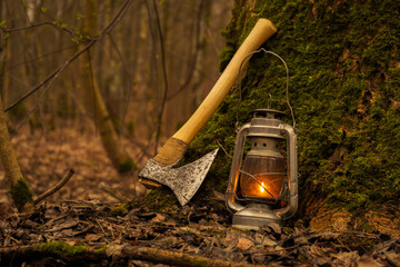 A kerosene lantern shines near an old ax