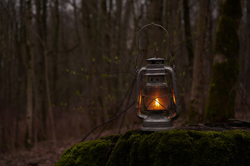Old kerosene lamp shines in the brown autumn leaves