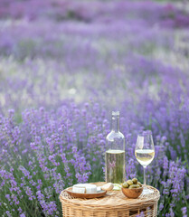Glass of white wine in a lavender field. Violet flowers on the background. - 784809968