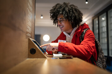 Curly-haired guy in eyeglasses buying tickets online and looking involved