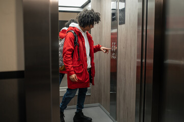 Guy in red jacket standing near elevator and pressing the button