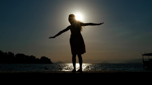 Child enjoy lovely nightfall lake. A silhouette of playful teen girl silhouette resting in sunset sea wind during summer weekend.