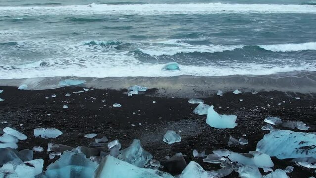 Aerial drone footage of Diamond beach, Iceland. Icebergs washed up on the black beach. Ice diamonds floating in diamond beach in Iceland. Scenic view of an Artic nature ice landscape. Climate change.