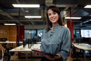 Two multiracial business woman in businesswear smiling while using digital tablet in office - 784823563
