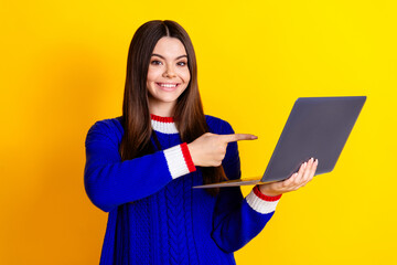Photo portrait of pretty teen girl hold point netbook wear trendy knitwear blue outfit isolated on yellow color background