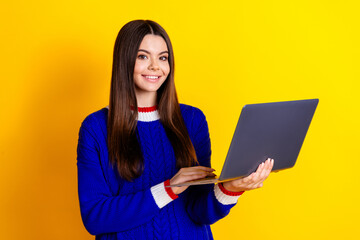 Photo portrait of pretty teen girl hold netbook wear trendy knitwear blue outfit isolated on yellow color background