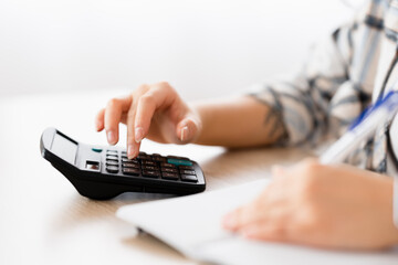 Close-up of a woman checking bills at home using calculator