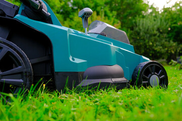 Garden equipment and tools.cutting grass close-up.Lawnmower on a mowed lawn close-up.  - obrazy, fototapety, plakaty