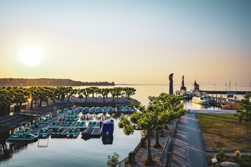 Tretboote im Hafen am Holzsteg vor Imperia-Statue, Graf Zeppelin, Leuchtturm und See im Hintergrund...