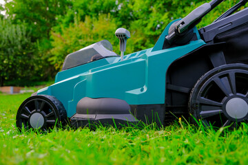 Mowing the grass in the garden.Garden equipment and tools.cutting grass close-up.Lawnmower on a mowed lawn close-up.  - obrazy, fototapety, plakaty