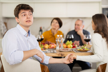 Fototapeta na wymiar Upset young guy at family holiday table with parents at home. Unpleasant discussion